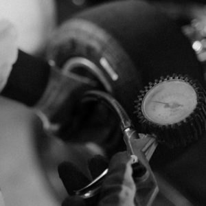 black and white photo of someone checking tire pressure