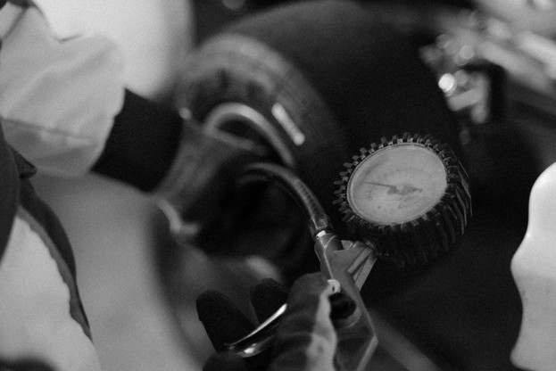 black and white photo of someone checking tire pressure