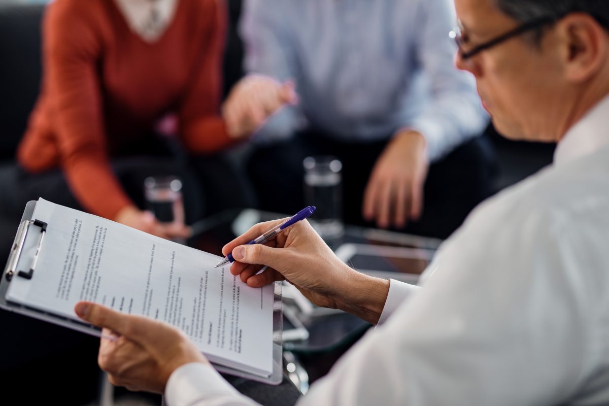 close up of agent going through lease agreement with clients sitting on couch