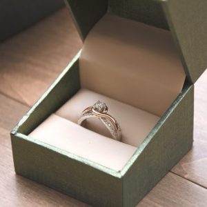 silver and gold colored ring in a green engagement box