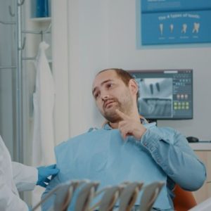 man at dentist pointing at tooth