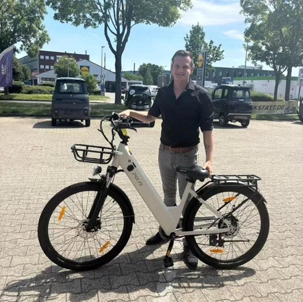 man in black shirt standing with ebike in parking lot