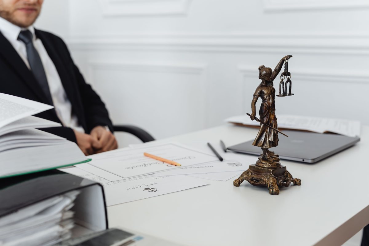 A legal professional's workspace featuring Lady Justice statue, documents, and a laptop.