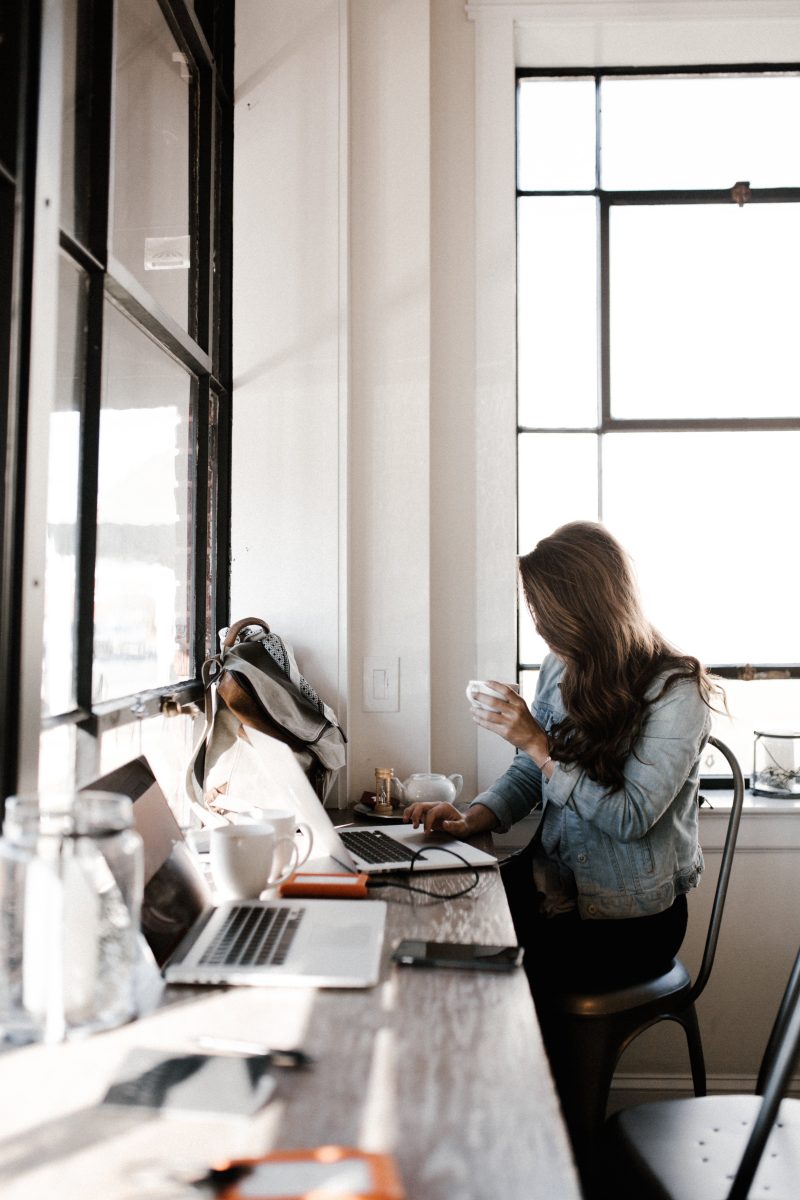 girl sitting at computer desk drinking coffee