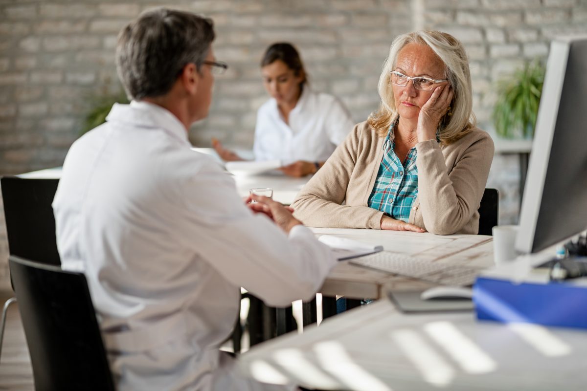 worried mature woman talking with a healthcare provider about medical insurance counseling clinic