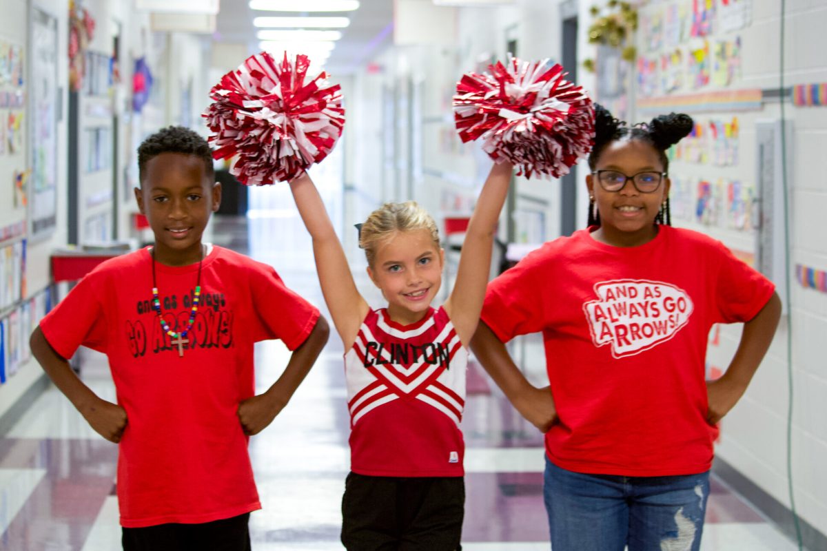 Northside Elementary students in red Arrows shirts cheering with pom-poms in a school hallway