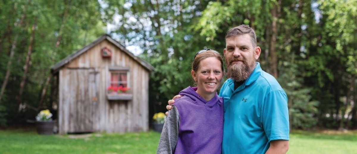 Ryan Groves and his wife standing in front of a wooden shed