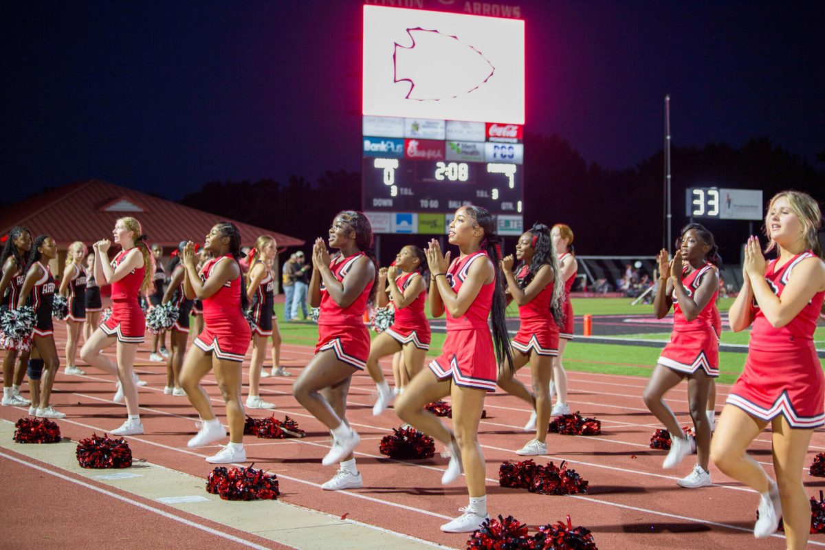 Clinton High School cheerleaders performing on the track during the Homecoming game at night