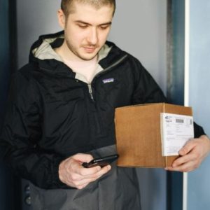 man holding a small delivery box and a phone