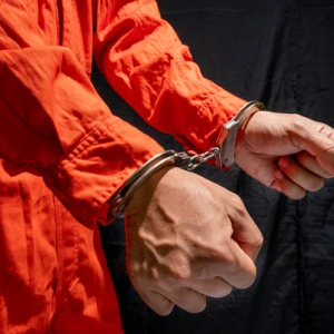 man in orange jumpsuit in handcuffs at jail