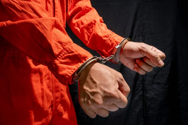 man in orange jumpsuit in handcuffs at jail