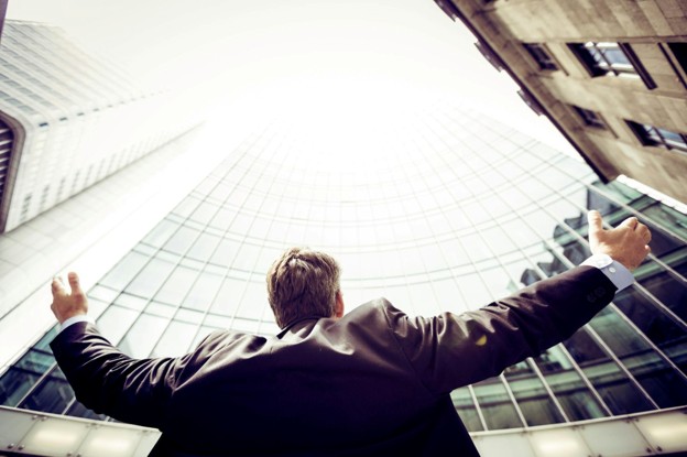 man lifting hands to a tall building