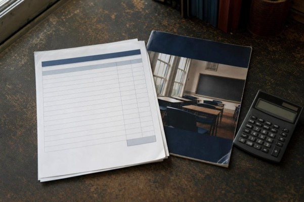 papers and calculator sitting on a wooden desk