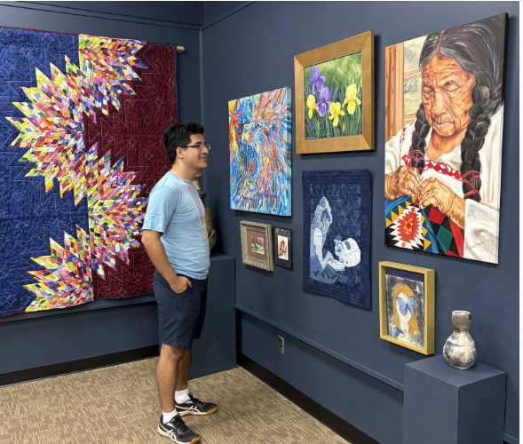 Alexander Perez of Houston, Texas, a graduate student in MC's Biology and Medical Sciences Program, peruses some of the pieces displayed in the “Art From Our MC Family” exhibit in the Samuel Marshall Gore Art Gallery.