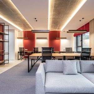 Spacious modern office featuring red accent walls, stylish furniture, and ample natural light.