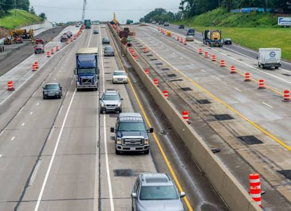 Motorcyclist approaching a road construction zone with temporary barriers and uneven pavement in Grand Rapids, Michigan.