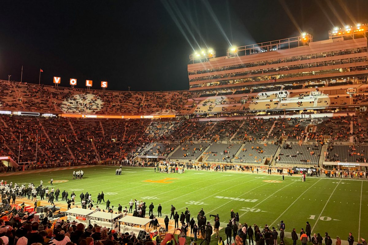 A packed college football stadium under bright lights at night
