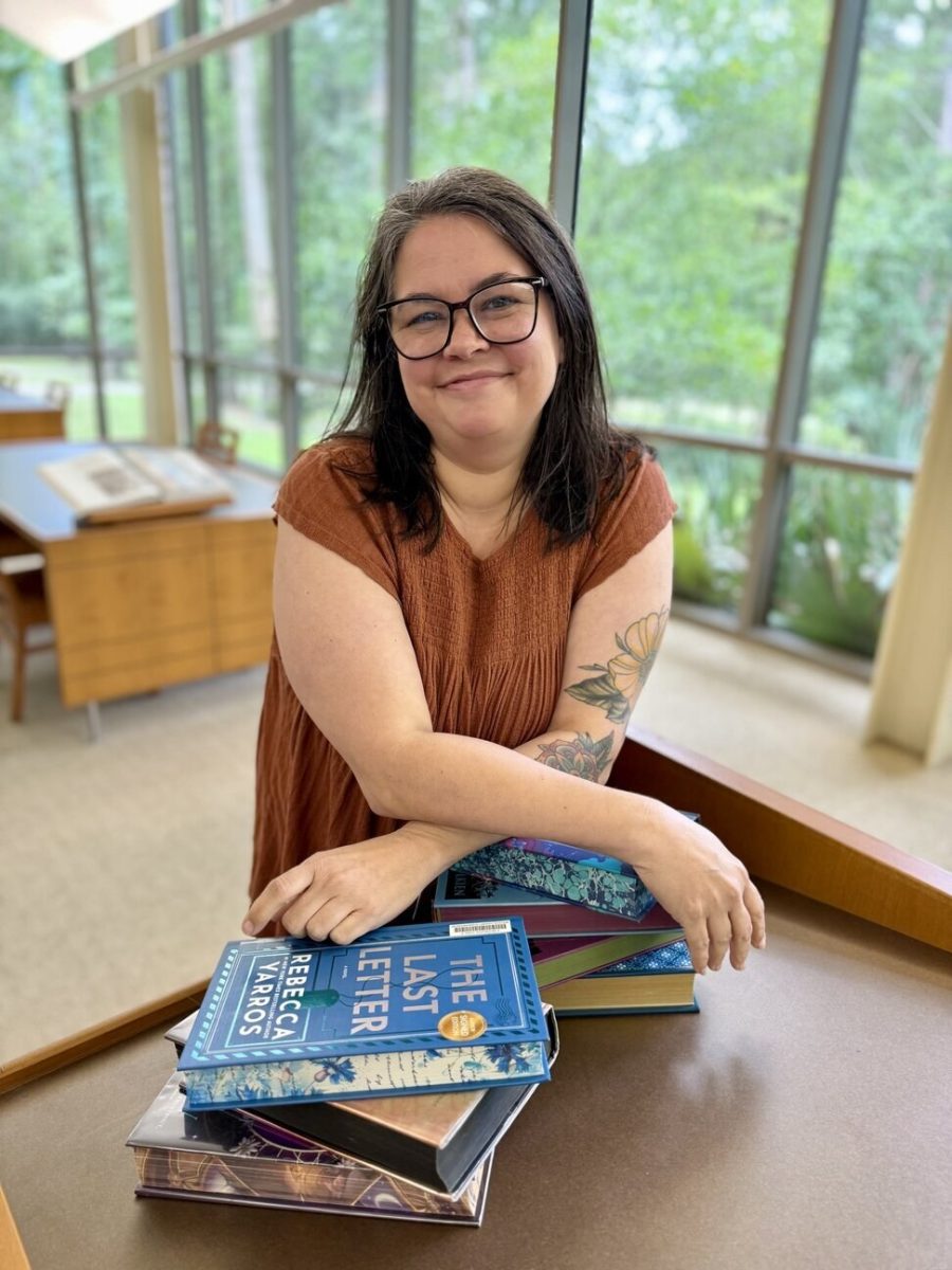 Kim Ellington, branch manager of the Quisenberry Library, seated at a table with a stack of books