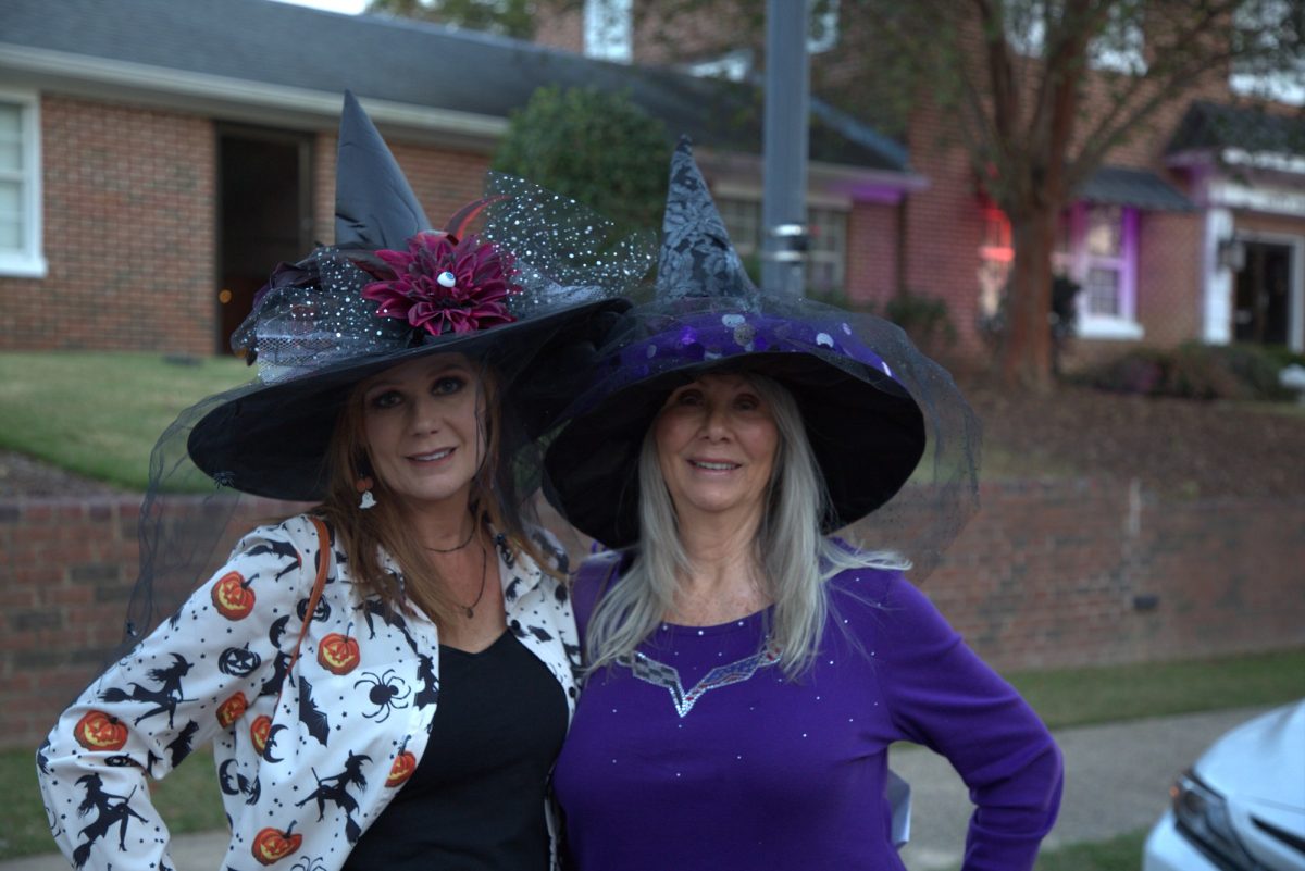 Two women in decorated witch hats posing outdoors