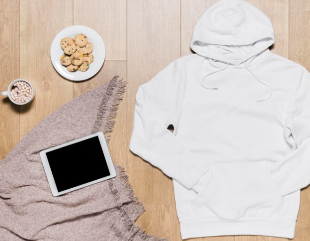 white hoodie on a wood backdrop with cookies, hot chocolate and an ipad on a blanket