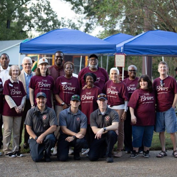 Briars neighbors, City officials and first responders posing together in front of blue tents