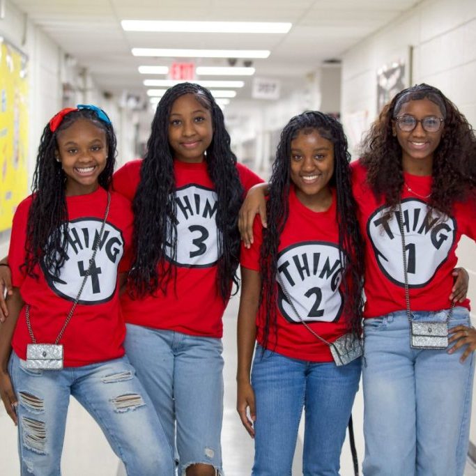 Four Clinton Junior High students in matching red Thing 1 through Thing 4 shirts in a school hallway