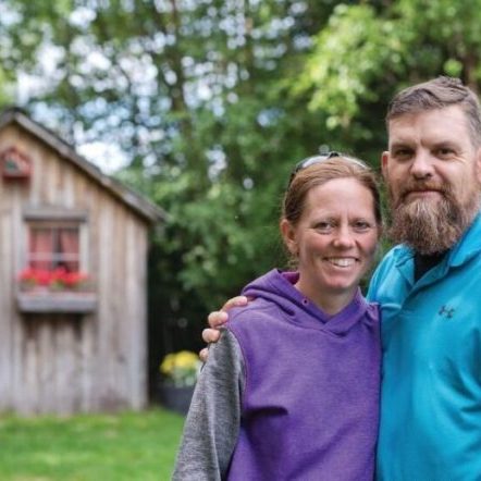 Ryan Groves and his wife standing in front of a wooden shed