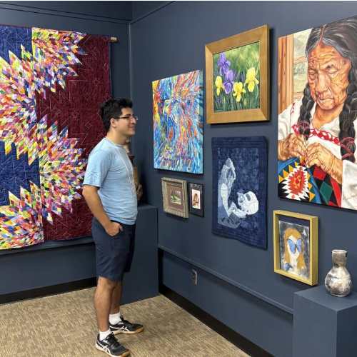 Alexander Perez of Houston, Texas, a graduate student in MC's Biology and Medical Sciences Program, peruses some of the pieces displayed in the “Art From Our MC Family” exhibit in the Samuel Marshall Gore Art Gallery.