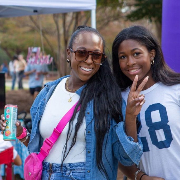 Two women smiling for a photo at an MC homecoming tailgate