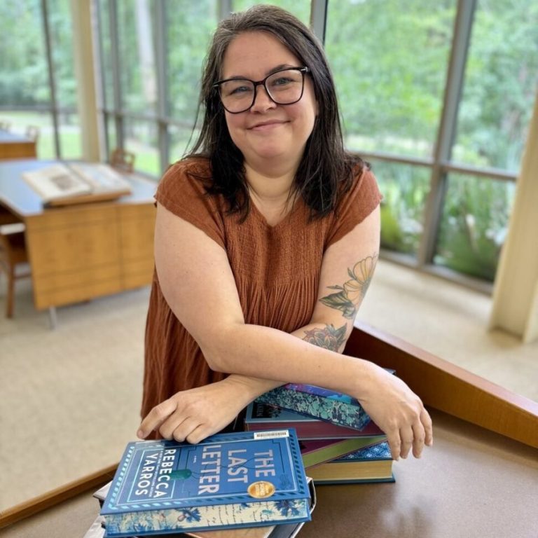 Kim Ellington, branch manager of the Quisenberry Library, seated at a table with a stack of books